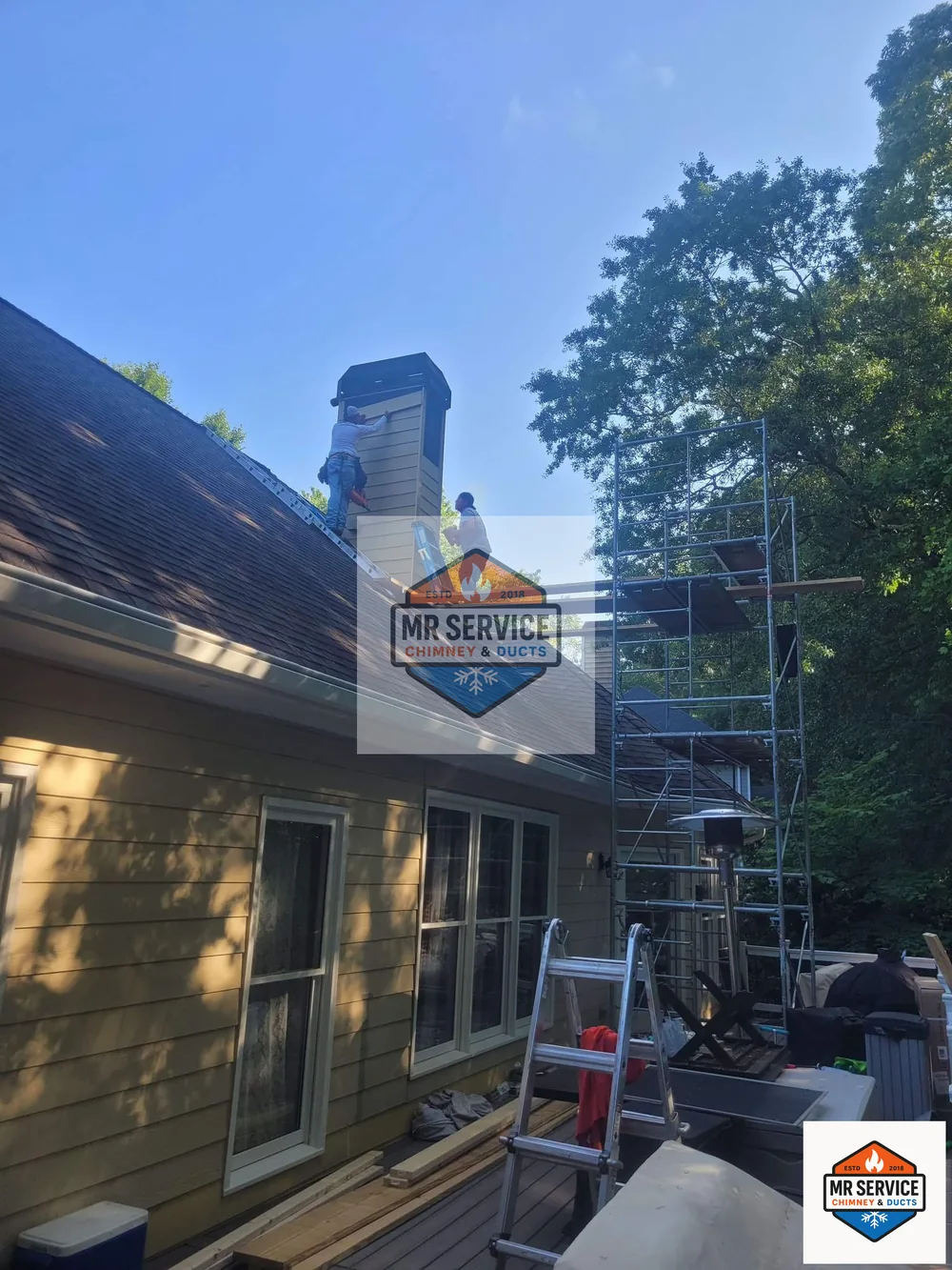 Technicians working from scaffolding on an exterior chimney chase