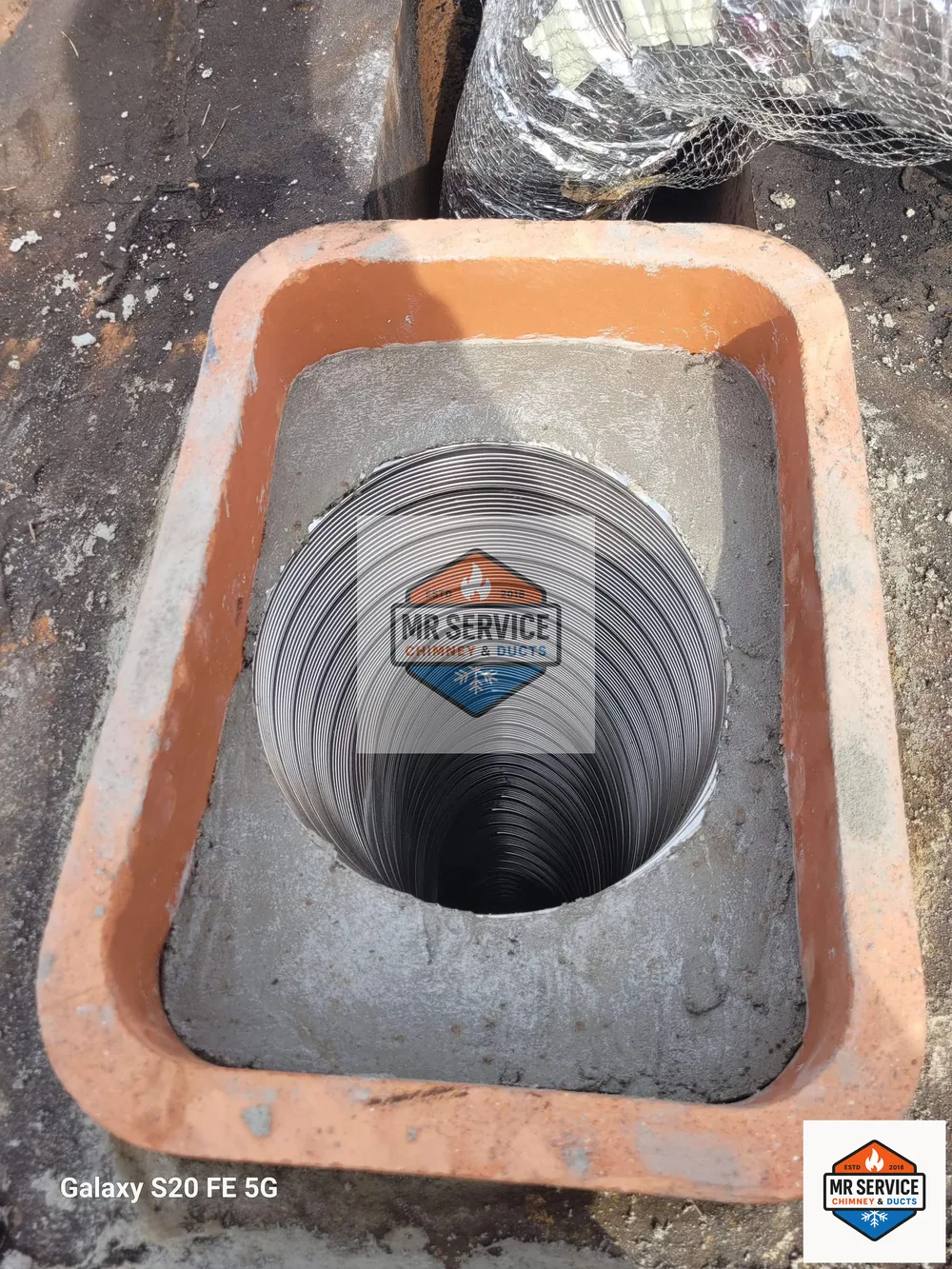 Stainless chimney liner being installed through a flue opening