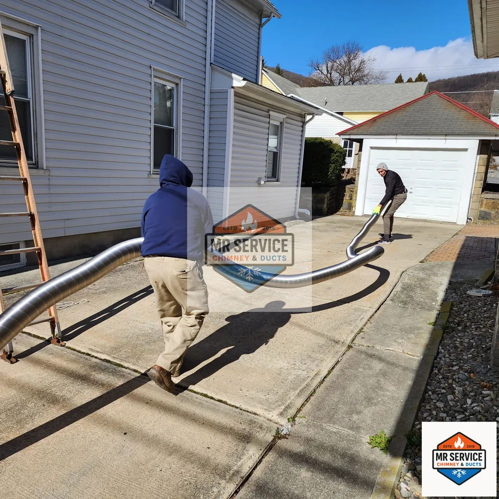 Technicians handling chimney liner material outside a home