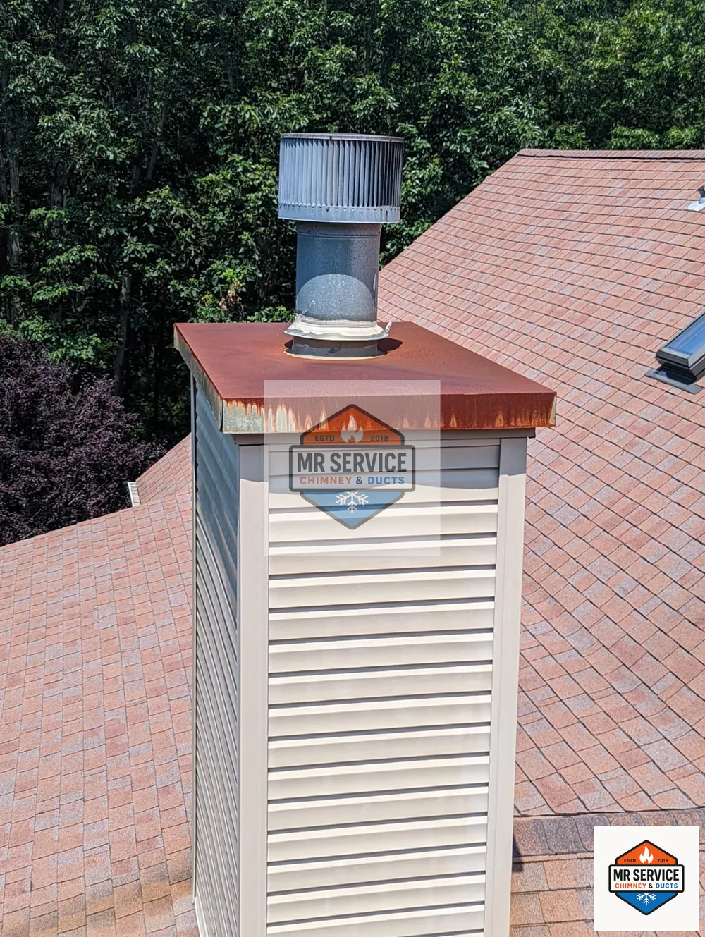 Rusted chimney cap and top components viewed from roof level